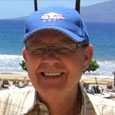 Profile picture of a man in hat with a beach behind him