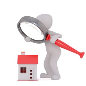 Clay figurine holding up a magnifying glass observing a small house